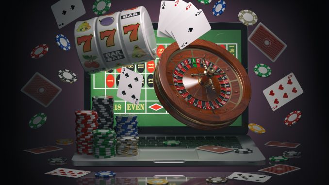Online casino concept. Laptop with roulette, slot machine, casino chips and playing cards isolated on black background. онлајн казино
